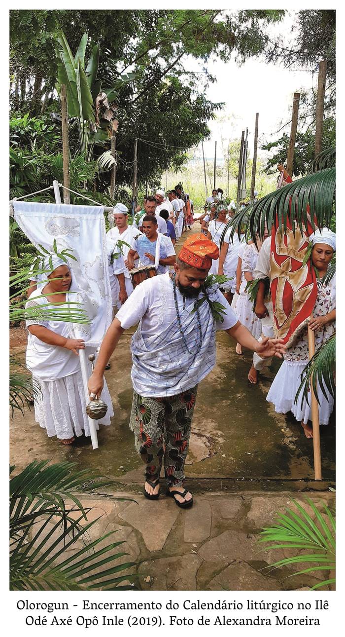   4 z. 1 Olorogun encerramento do calendário litúrgico no Ilê Odé Inle( 2019) Foto de Alexandra Moreira Foto colorida em que se retrata homens e mulheres trajando roupas brancas. Usando turbantes e portando bandeiras coloridas, todos seguem em procissão. Realização: Academia Planaltinense de Letras, Artes e Ciências (APLAC), pelo Ecomuseu Pedra Fundamental e pelo Coletivo Nativo Audiodescrição produzida  pelo Instituto de Promoção das Pessoas com Deficiência Visual Audiodescritora: Elma Lúcia Rodrigues Consultor: Fernando Rodrigues Este projeto é promovido com recursos do Fundo de Apoio a Cultura do DF